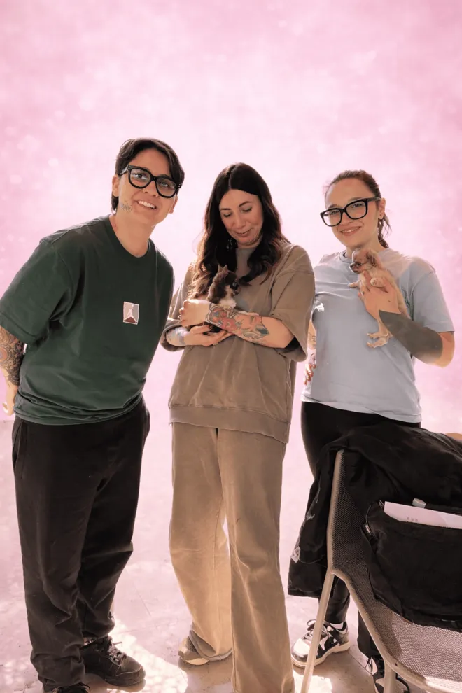 Tre amici in studio su fondo rosa con due cuccioli di Villa Chihuahua in braccio