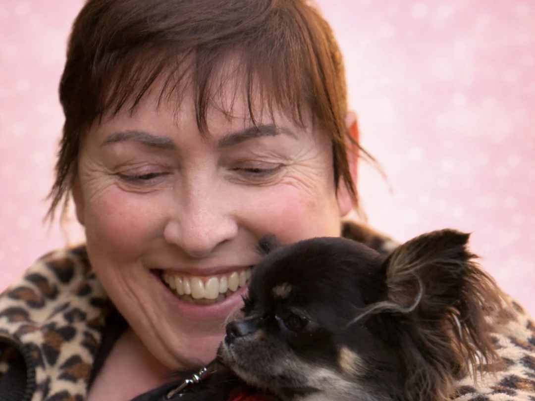 Una donna sorride abbracciando il proprio Chihuahua